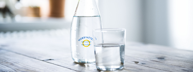 Vattenkaraff med Norrvattens logotyp  och glas med vatten