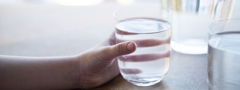 Hand som håller i ett glas med vatten